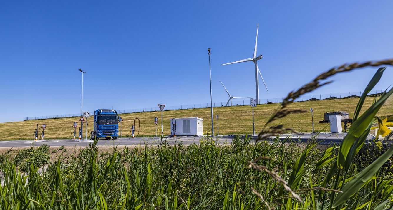 Laadplein voor elektrische vrachtwagens met blauwe vrachtwagen en windmolens
