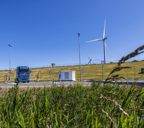 Laadplein voor elektrische vrachtwagens met blauwe vrachtwagen en windmolens