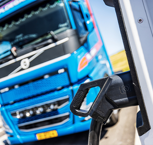 Laadpaal van elektrische vrachtwagens met blauwe vrachtwagen op de achtergrond