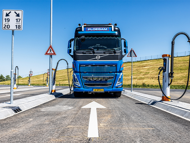 Voorkant van een blauwe elektrische Ploegam vrachtwagen aan het opladen op laadplein