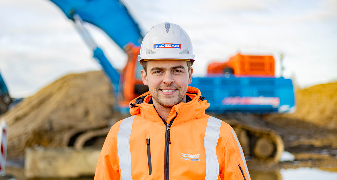 Medewerker Ploegam met oranje jas en helm op bouwplaats met blauwe kraan