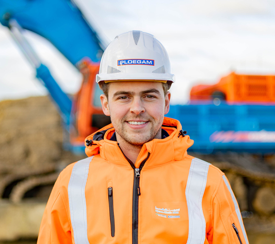 Medewerker Ploegam met oranje jas en helm op bouwplaats met blauwe kraan