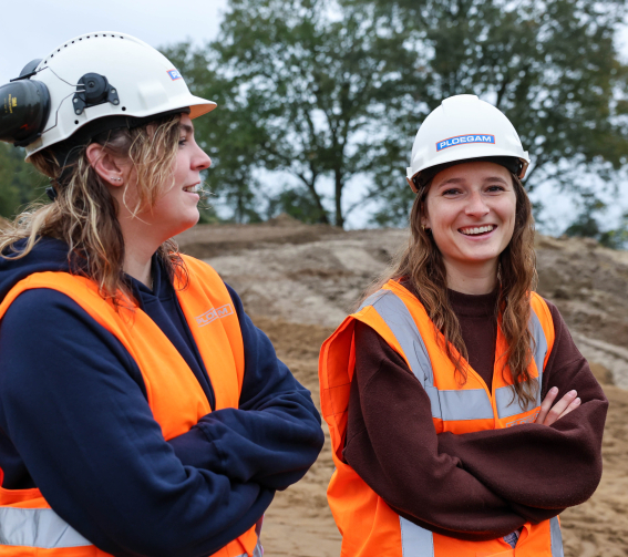 Ploegam medewerker met oranje jas en helm op een bouwplaats