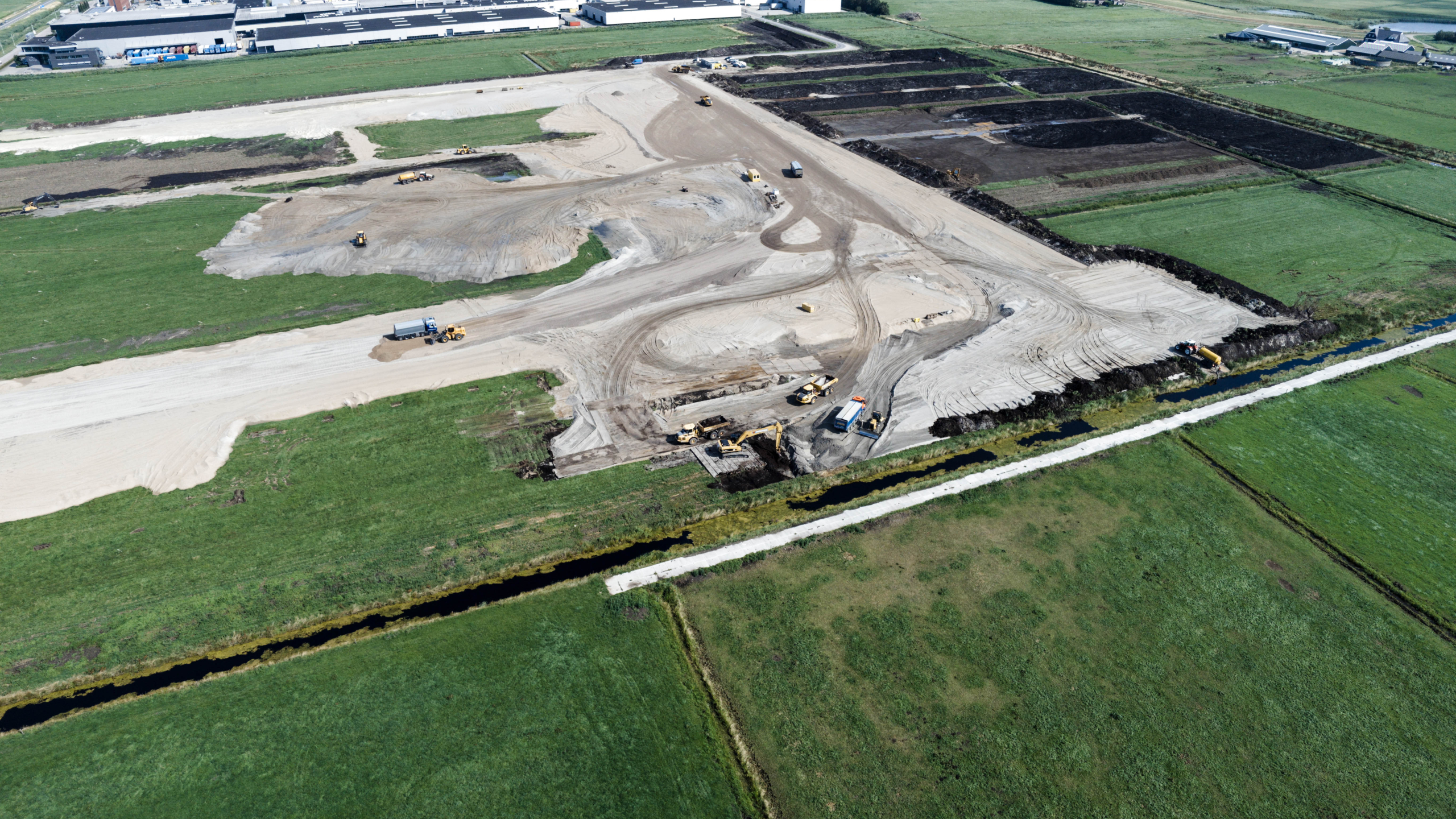 Luchtfoto van werkzaamheden in het zand tussen de groene weilanden