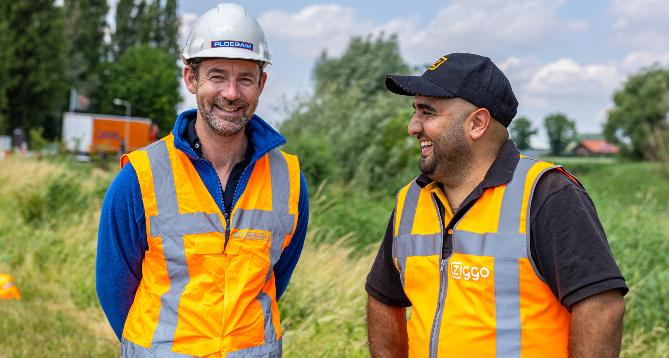 Medewerker Ploegam met oranje veiligheidsjas en witte helm op bouwplaats