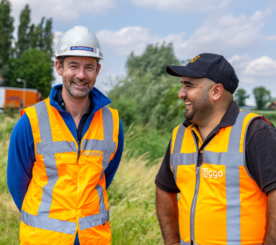 Medewerker Ploegam met oranje veiligheidsjas en witte helm op bouwplaats